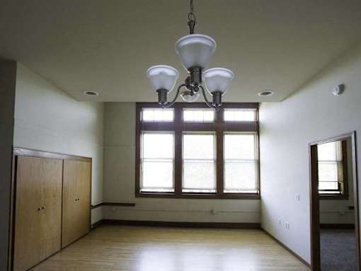 A room with a large window and a chandelier hanging from the ceiling.