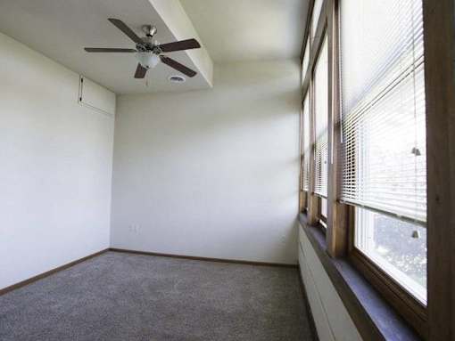 A room with a ceiling fan and a window with blinds.