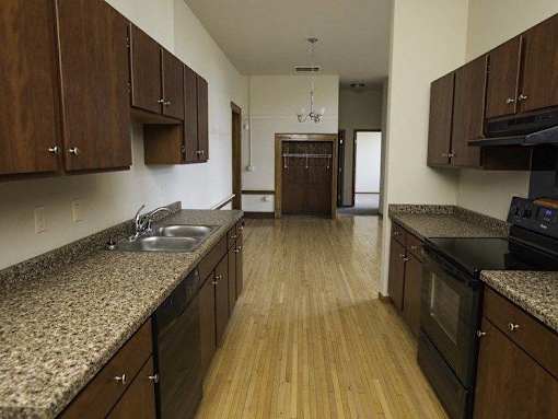 A kitchen with wooden floors and dark brown cabinets.