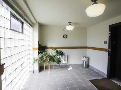 A hallway with a tiled floor, a trash can, and a plant.