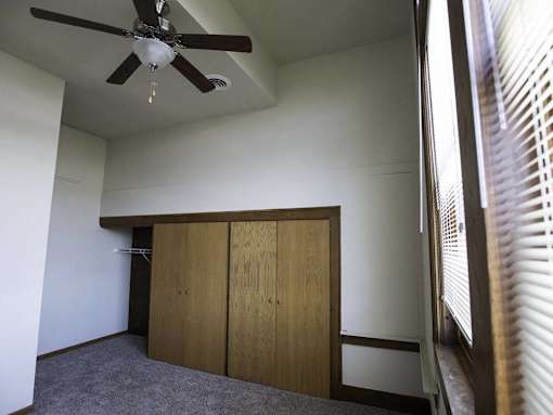 A room with a ceiling fan and a window with blinds.