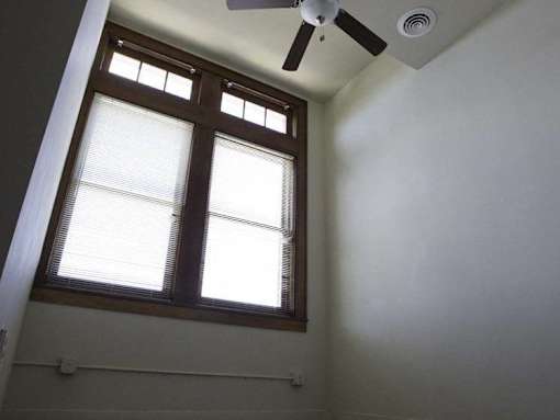 A room with a ceiling fan and a window with blinds.