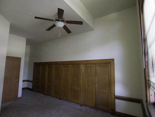 A room with a ceiling fan and a large wooden wardrobe.