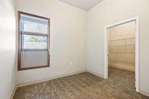 A room with a carpeted floor, a window, and an open door.
