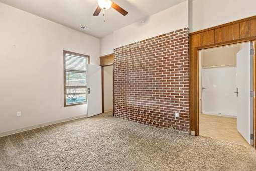 A room with a brick wall and a ceiling fan.