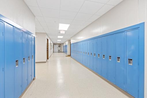 A long hallway with blue lockers on both sides.