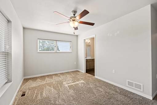 A room with a ceiling fan and carpeted floor.