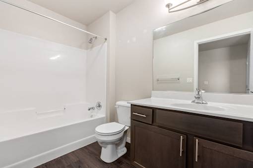 A white toilet sits in a bathroom with brown cabinets.