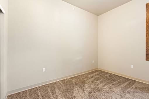A room with a carpeted floor and a painting on the wall.