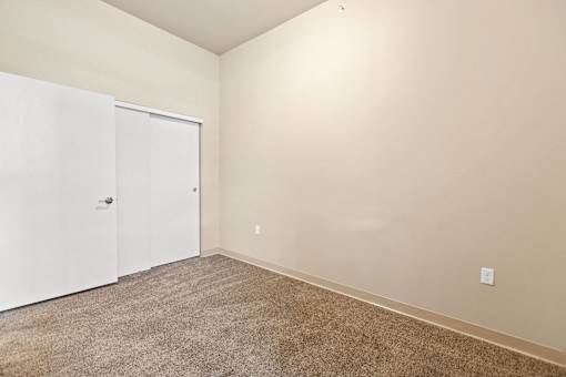A room with a white door and carpeted floor.