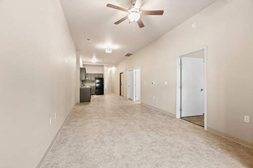 A long hallway with a fan and a door on the right.