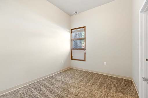 A room with a carpeted floor and a window with blinds.