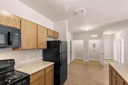 A black refrigerator in a kitchen with wooden cabinets.