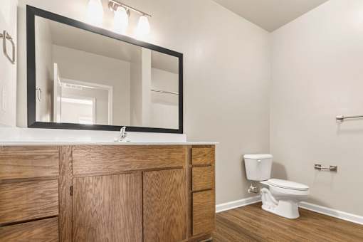 A bathroom with a wooden vanity and a white toilet.