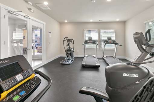 A gym with treadmills, elliptical machines, and a treadmill with a digital display.