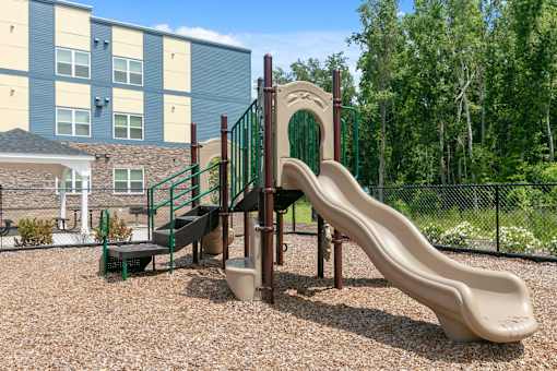 A playground with a slide and a green fence.