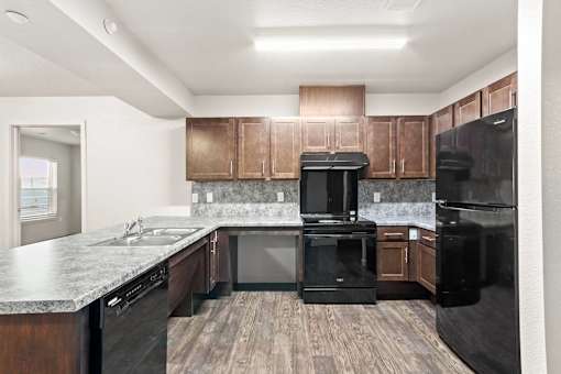 A kitchen with black appliances and wooden cabinets.