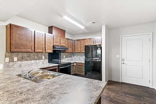 A kitchen with a sink, stove, and cabinets.