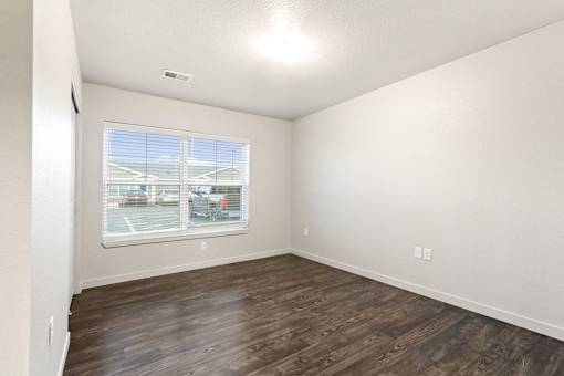 Empty room with a window and wooden flooring.