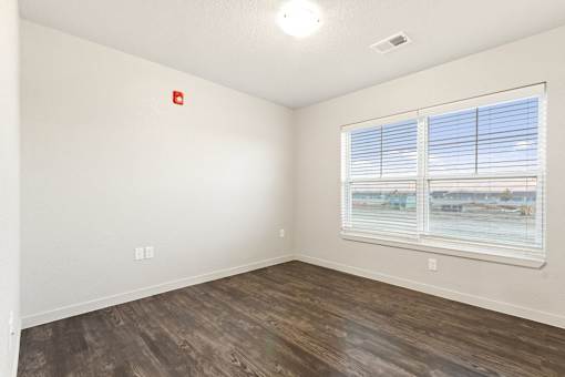 A room with a window and a wooden floor.