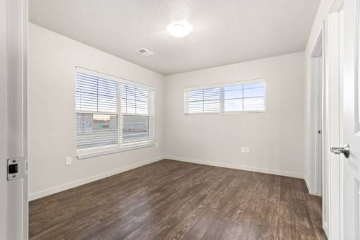 A room with wooden flooring and a window with blinds.