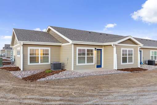 A beige house with a dark roof and a blue door.