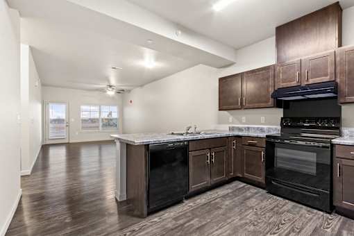 A kitchen with dark wood cabinets and black appliances.