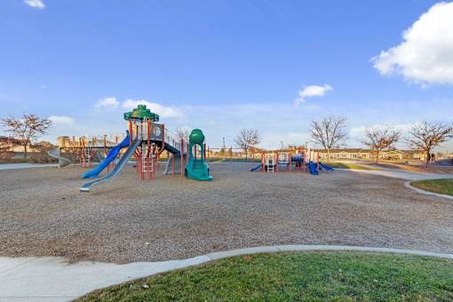 A playground with a green and blue slide and a red swing set.