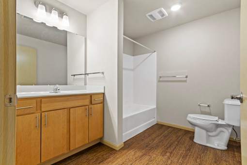 A white toilet sits in a bathroom with wood floors and white walls.
