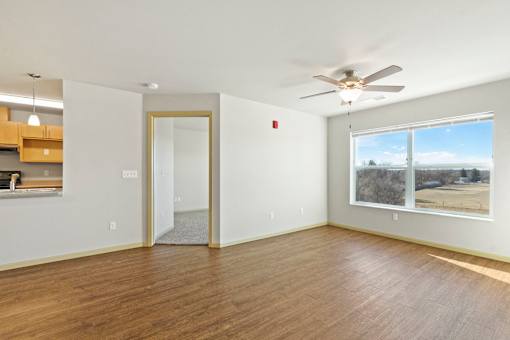 A room with a ceiling fan and a large window.