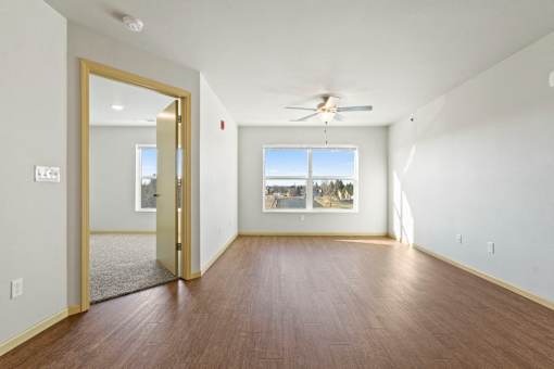 A room with a ceiling fan and a large window.
