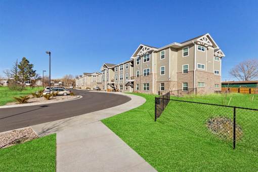 Apartment complex with a green lawn and a walkway.