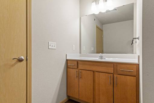 A bathroom with a wooden door and a mirror above a sink.