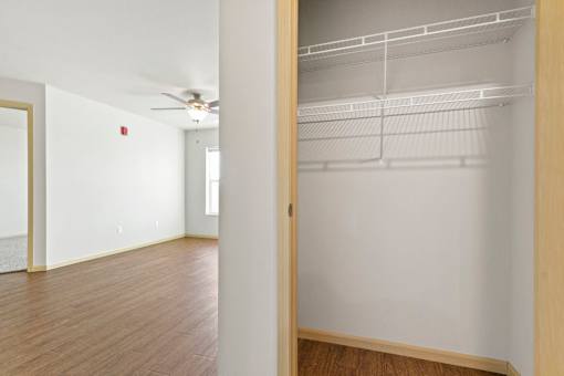 A white room with a wooden floor and a white wall with a door on the right.