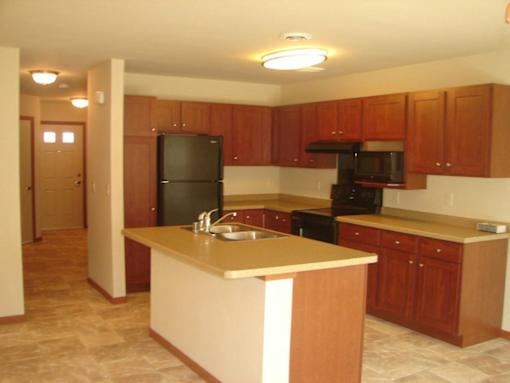 A kitchen with wooden cabinets and a black refrigerator.