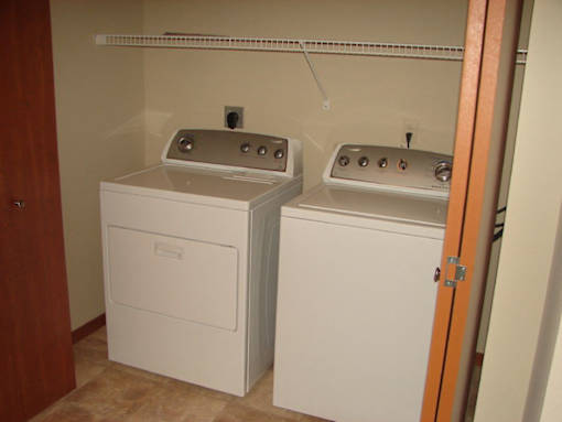 Two white washing machines in a small room.