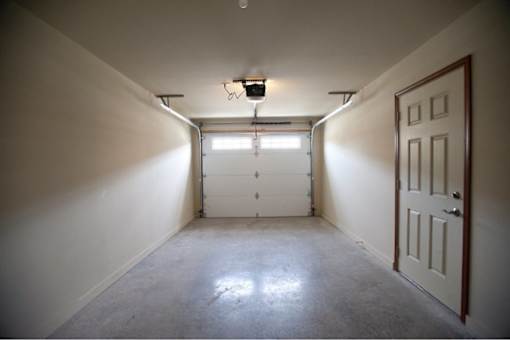 A white door is on the right side of a room with a concrete floor.