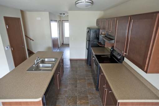 A kitchen with brown cabinets and a black refrigerator.