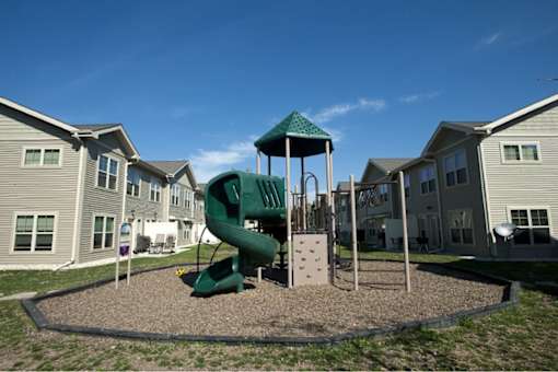 A playground with a green slide and a green canopy.