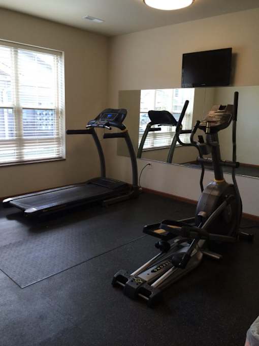 A home gym with a treadmill, a stationary bike, and a chair.