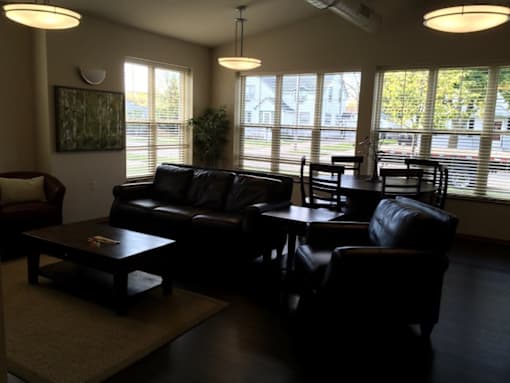 A living room with a black leather couch and a coffee table.