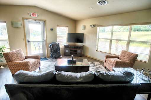 A living room with a couch, chairs, and a television.