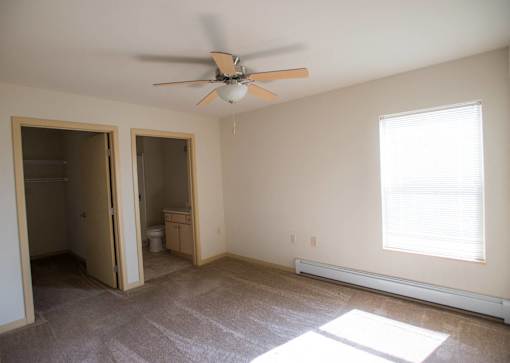 A room with a ceiling fan and a window with blinds.