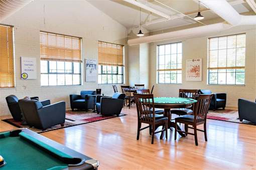 A room with a pool table and a few chairs.