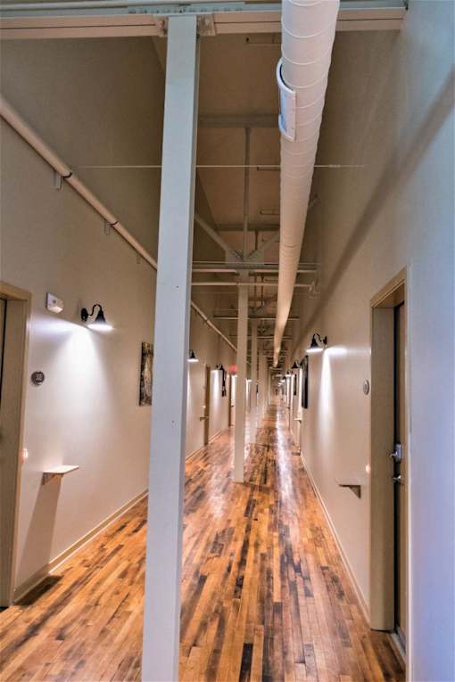 A long hallway with wood floors and white walls.