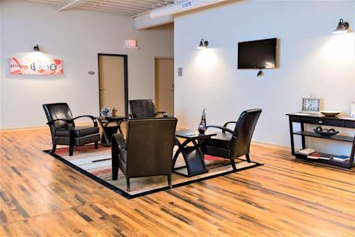 A conference room with a wooden floor and a white wall with a TV.