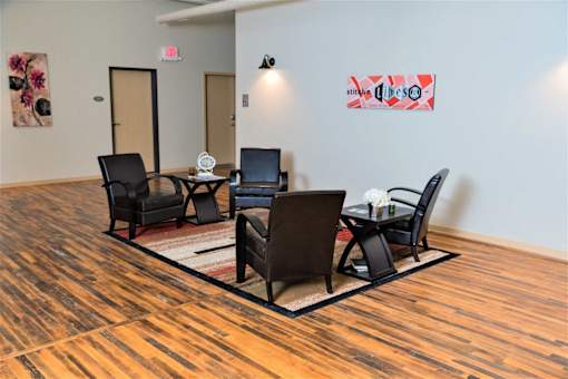 A conference room with a wooden floor and a white wall with a red and white poster.