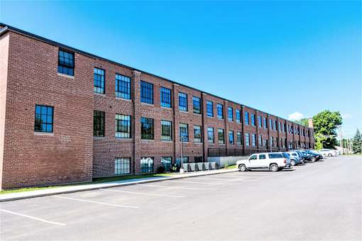 A long brick building with a parking lot in front.
