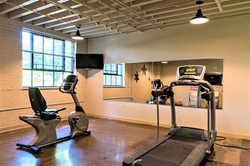 A gym with a treadmill and a stationary bike.