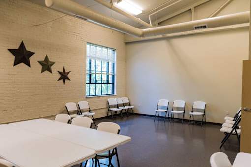 A room with white tables and chairs and three stars on the wall.
